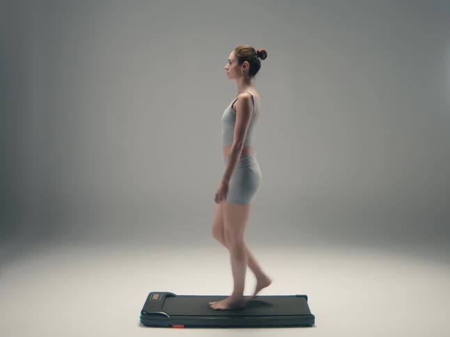 Woman walking on a low treadmill in a side view