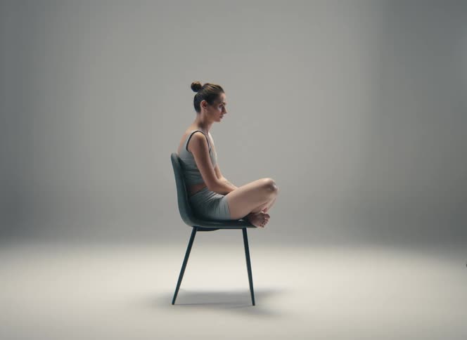 Woman seated on a chair with crossed legs resting on the seat