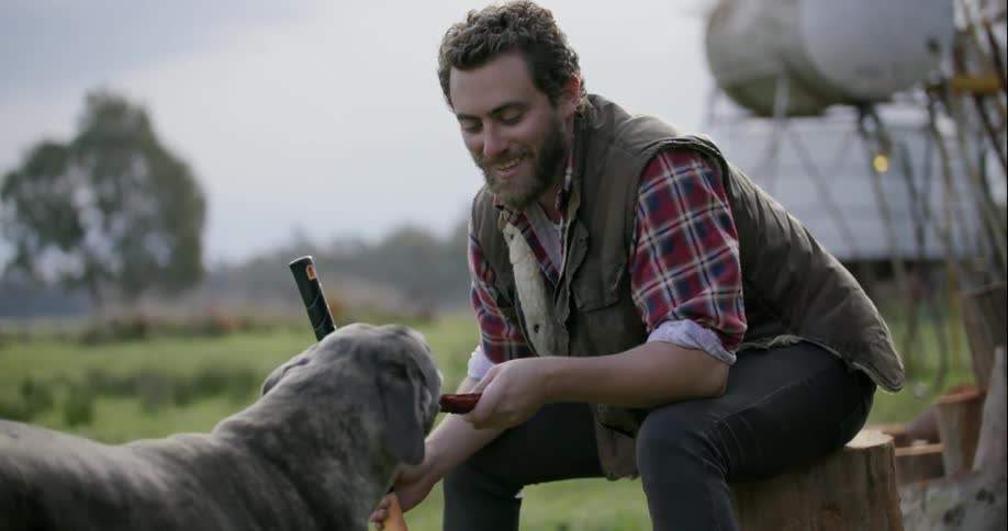 A man sits outside petting his dog