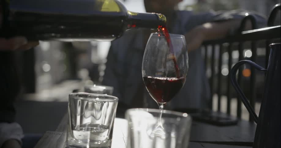 A person pours wine into a glass outside