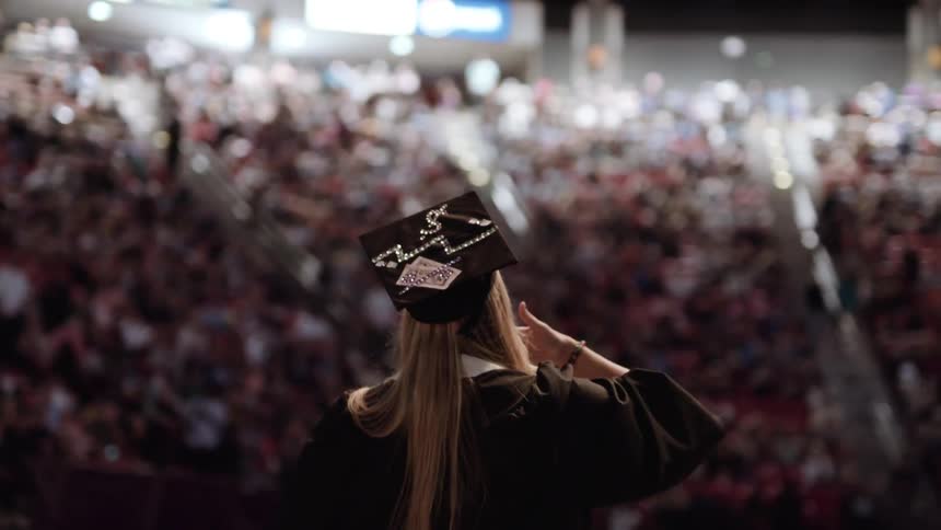 A woman blows kisses at the audience at a graduation ceremony