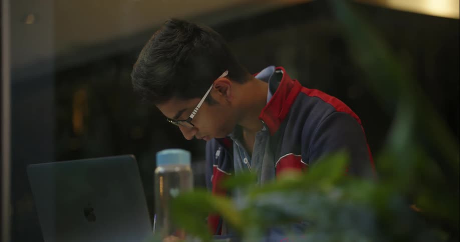 A man sitting at a table outside and working on a laptop