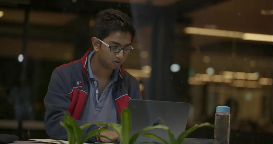 Man types on laptop inside a shop