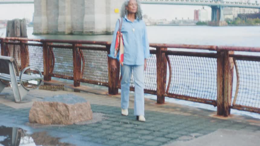 A woman walking outdoors near a bridge