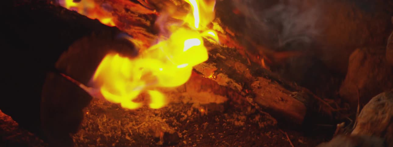 Bright yellow flames consume burning wood and ash