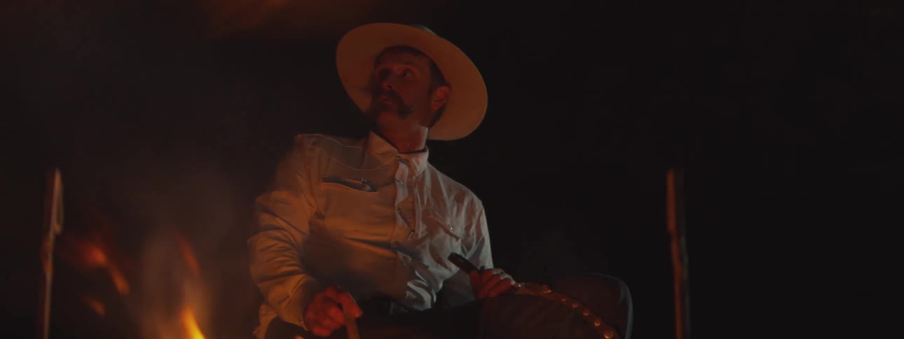 A man sitting outdoors next to a fire