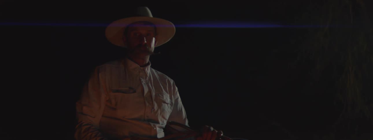 The campfire flickers on the man