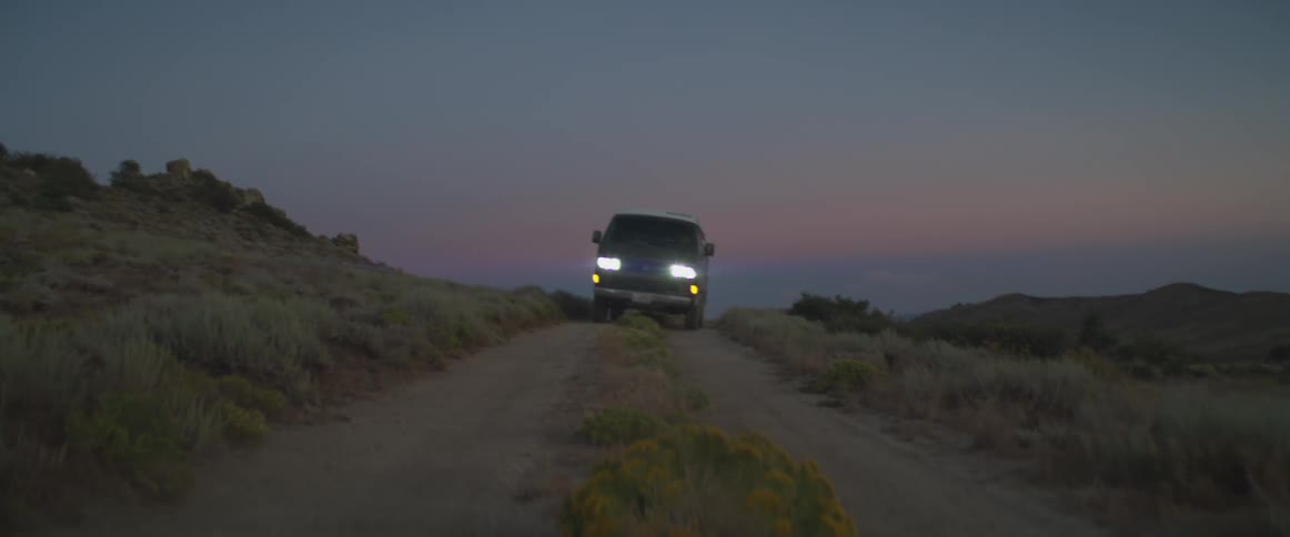 Truck traveling on a mountain dirt road with headlights on