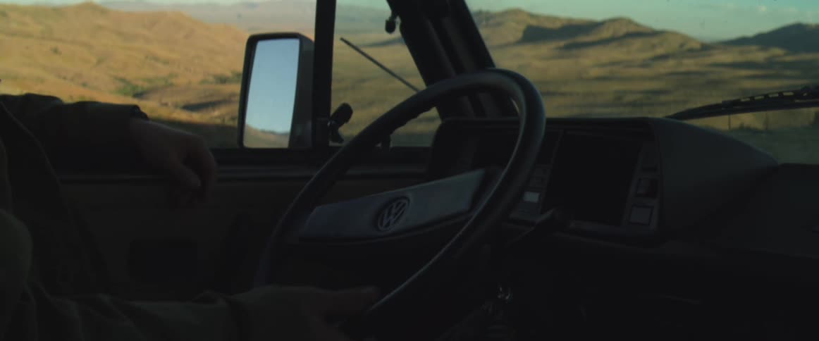 Interior of a volkswagen vehicle with the steering wheel framed against a mountainous landscape