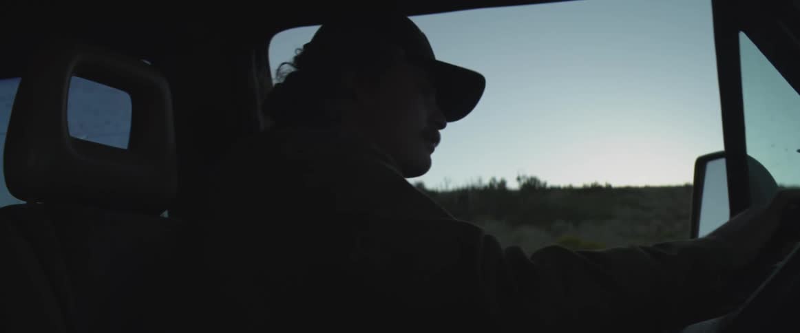 Man looks out the window as he drives on a rural road