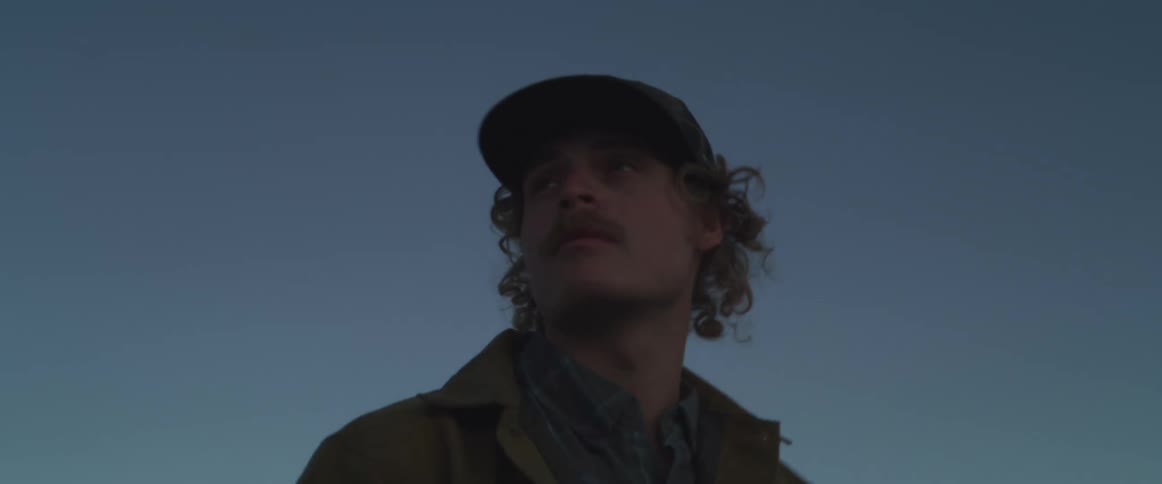 Man wearing a cap looking to the side under a blue sky
