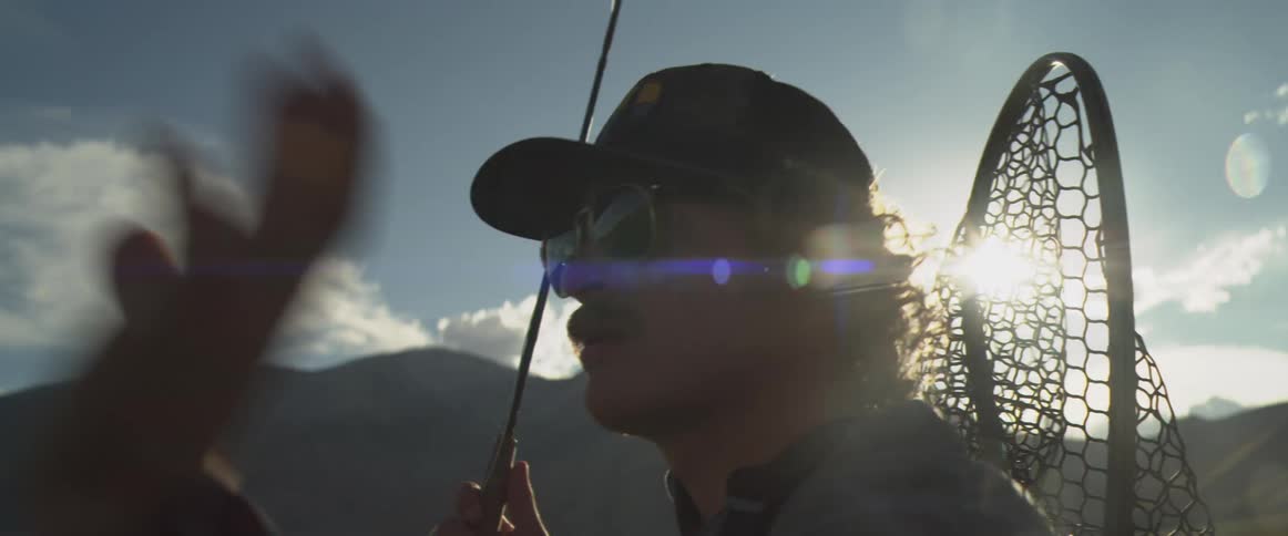 Man holds his fishing pole with a fishing net on his back