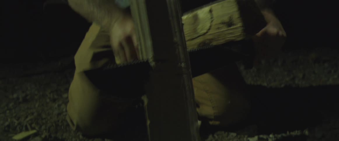 Man handling wooden logs in the dark