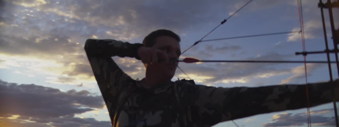 Archer raises his bow and pulls back his arrow as he releases the string and the arrow flies