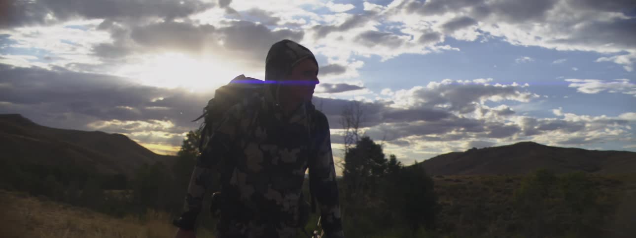 The hunter walks on the field with his bow