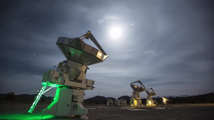 Satellite dishes in the desert turn and move as stars and clouds move over the sky