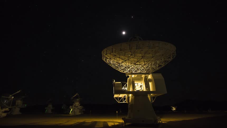 Dish antennas on a ground station outdoors during sunset and night time