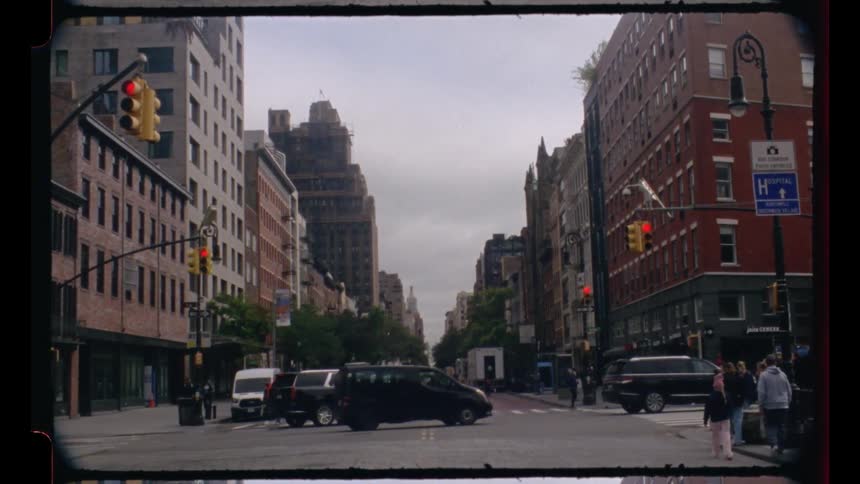 Urban intersection with stopped cars and pedestrians on sidewalks between tall buildings