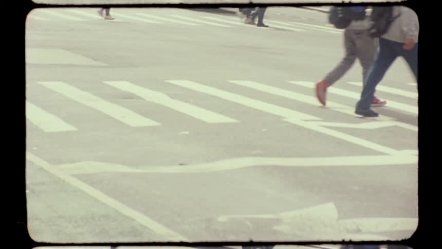 People cross the zebra crossing on the road at midday in the city while a cyclist rides by across the street