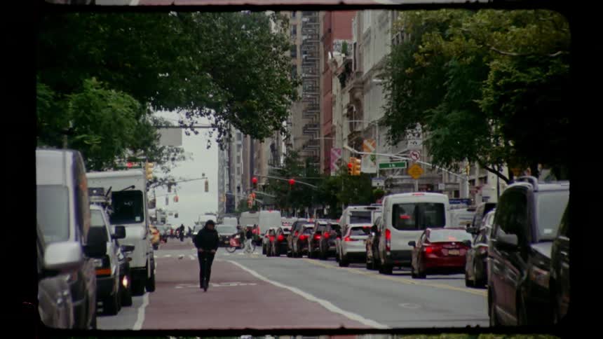Urban street with a line of cars and a pedestrian walking along the median