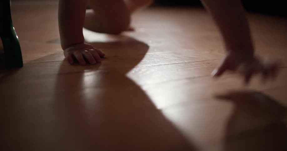 The baby crawls on the wood flooring