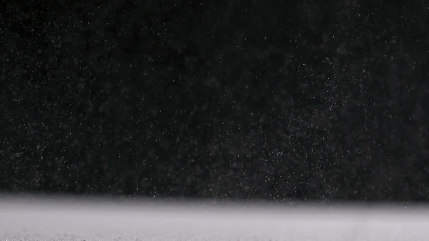 Snow drifts gently from the night sky shimmering as it falls through the darkness and settles quietly below