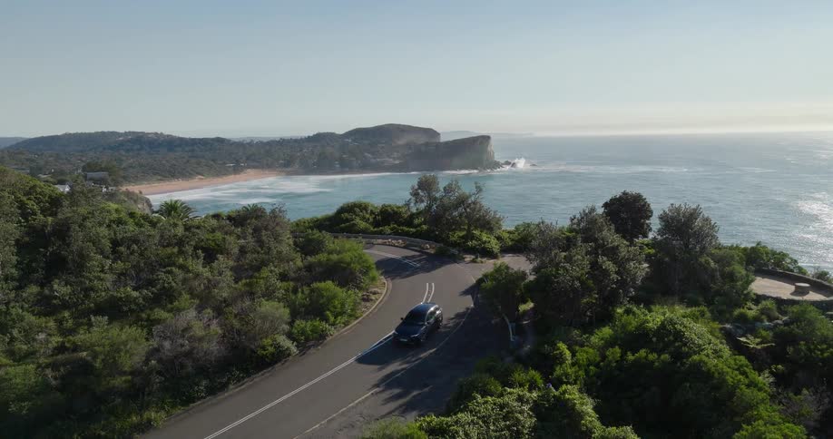 Car travels on a road around a curve overlooking the coast