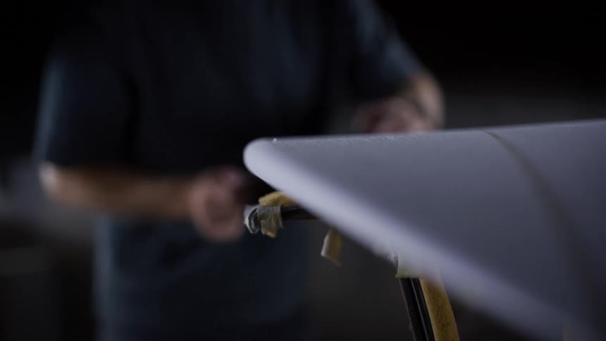 Man sanding the edge of a board supported on a stand