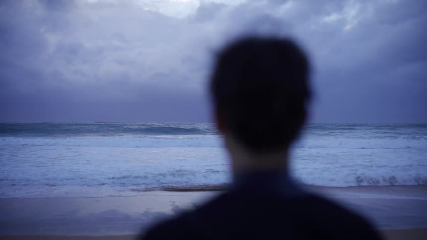 Blurred surfer in the foreground facing strong waves in the background