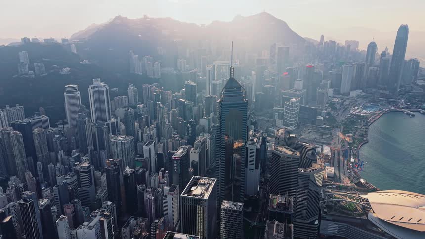Dense urban landscape with skyscrapers spread along the waterfront and mountains in the background