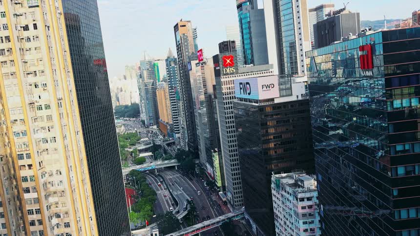 Modern high rise towers and skyscrapers stand tall in the metropolitan sky as cars travel on the streets