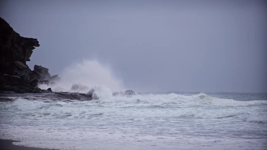 Strong waves crashing against rocks at the edge of the beach
