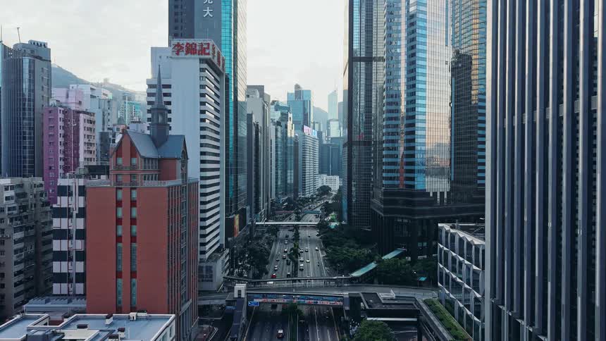 Urban avenue lined with skyscrapers with traffic flowing between the business buildings