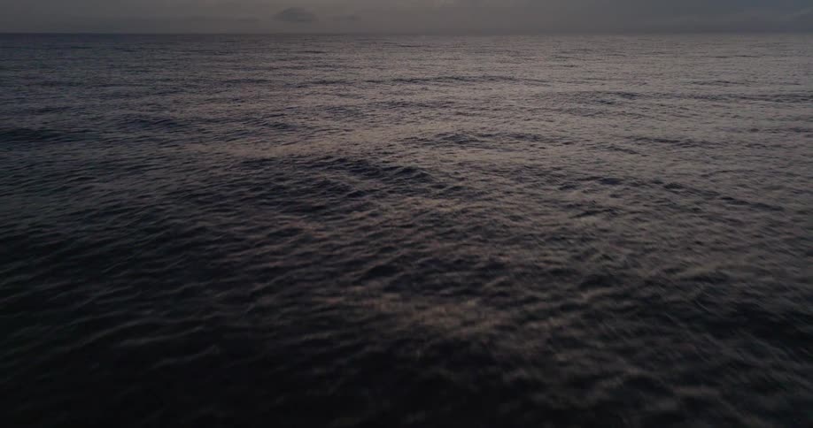 Calm sea at dusk with the horizon darkened by low clouds