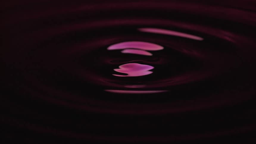 Dark purple liquid forming a central rise with ripple rings around it