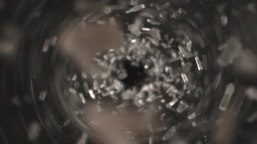 Gray fragments swirling in a downward motion inside a circular flow