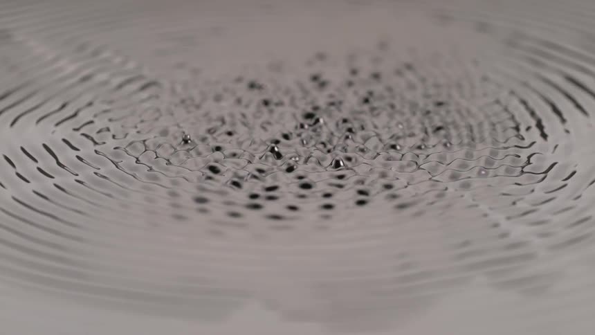 A black liquid is vibrating and popping up liquid is moving up