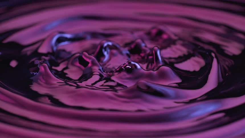 Water ripples outward in a spiral pattern as bubbles rise from the disturbance all illuminated by a soft purple glow