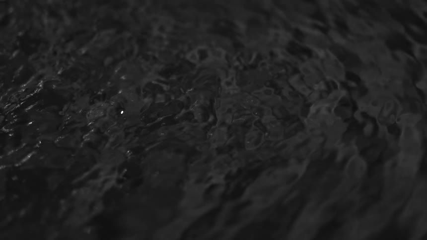 Dark liquid with a disturbed surface forming small irregular ripples