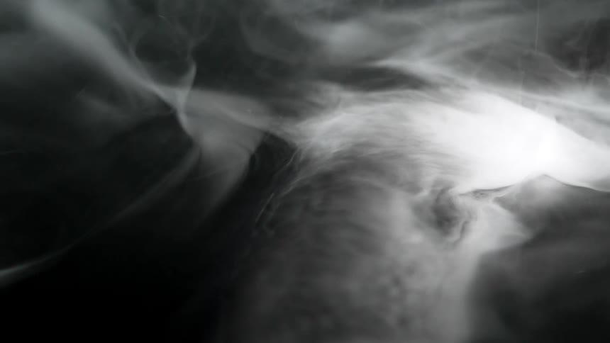 White smoke spreading in an irregular flow over a dark background