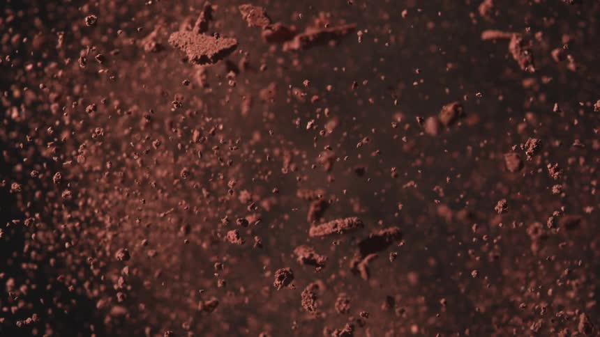 Brown dust particles expanding in dispersion against a dark background