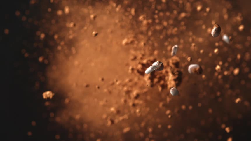 Lightcolored stones suspended among dispersing brown dust particles