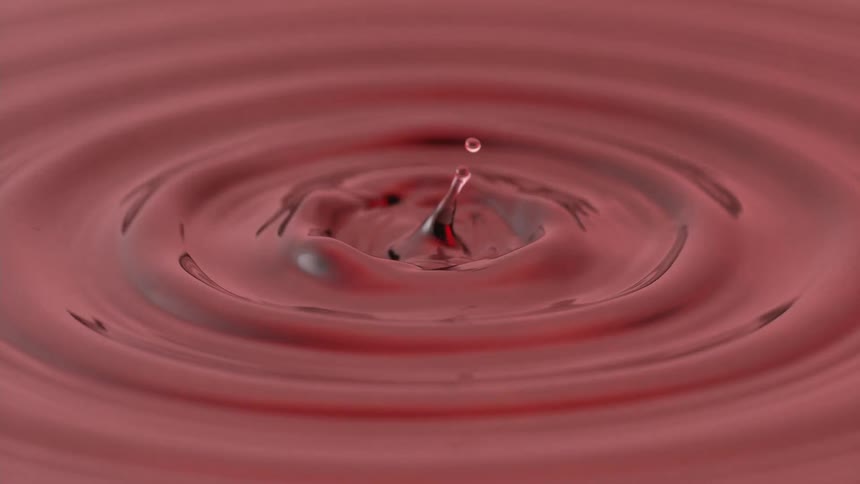 A red liquid ripples in a circular motion then begin making large droplet splashes