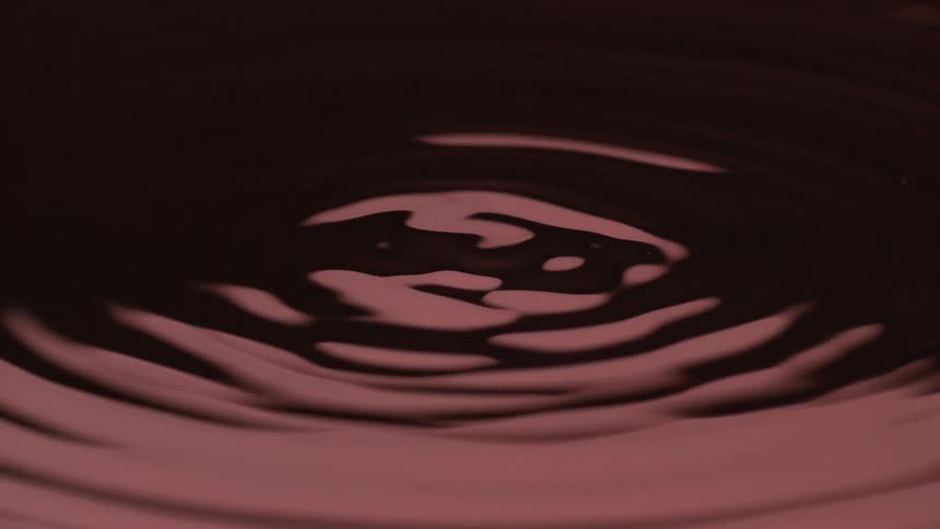 Dark red liquid forming small elevations and ripples after impact