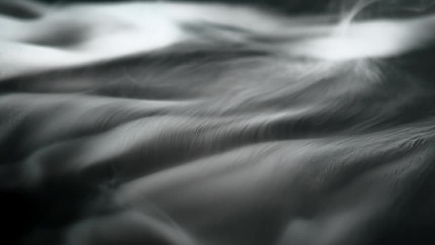 Abstract dark grey and white waves of flowing fabric or liquid fill the entire frame