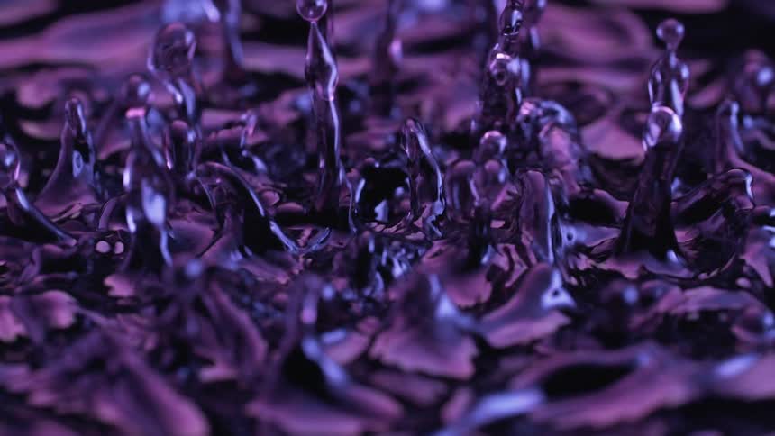 An abstract closeup reveals a dark liquid surface reacting to intense vibrations creating standing waves and launching droplets upward in a chaotic dance under moody purple lighting