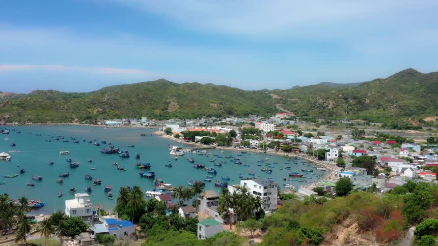 Coastal view with a town surrounding a bay filled with boats and mountains in the background