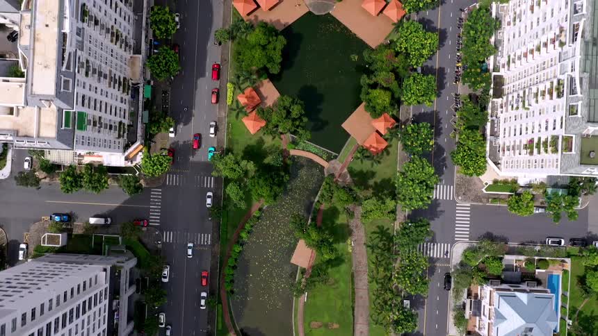 Aerial view of a neighborhood of tall apartment buildings and trees in a park with traffic on the streets