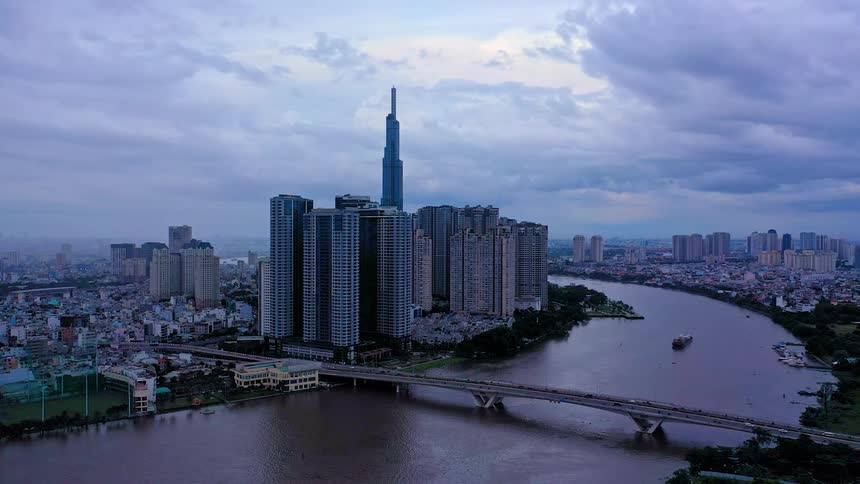 Aerial view of a metropolitan city on the coast of a river with boats on the water and traffic crossing the bridge