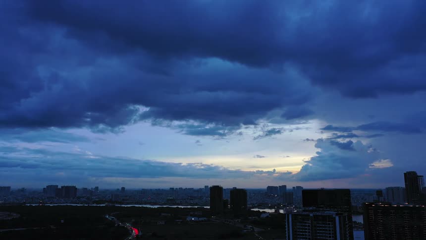 A city skyline at sunset dark clouds masking the fading light